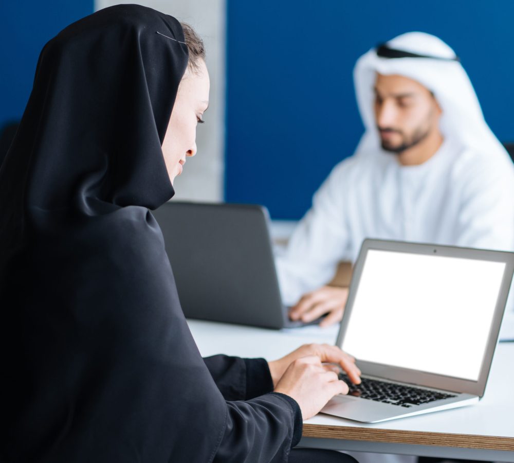 Man and woman with traditional clothes working in a business office of Dubai. Portraits of  successful entrepreneurs businessman and businesswoman in formal emirates outfits. Concept about middle eastern cultures, lifestyle and professional occupations